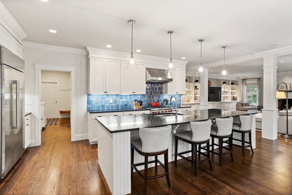 244 Musterfield Road Concord, MA 01742 - Photo 14 of 41 a kitchen with stainless steel appliances kitchen island granite countertop a table chairs stove and white cabinets