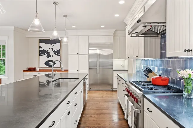a kitchen with stainless steel appliances granite countertop a sink a stove and a wooden floors