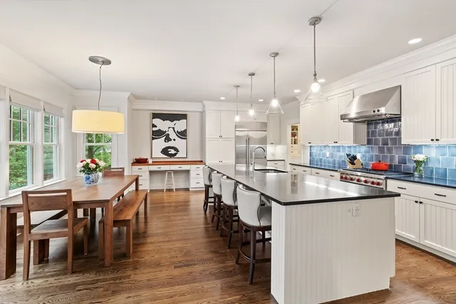 a open kitchen with stainless steel appliances granite countertop a stove and chairs with wooden floor