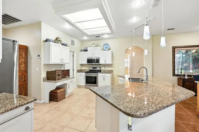 a kitchen with kitchen island granite countertop a stove sink and refrigerator