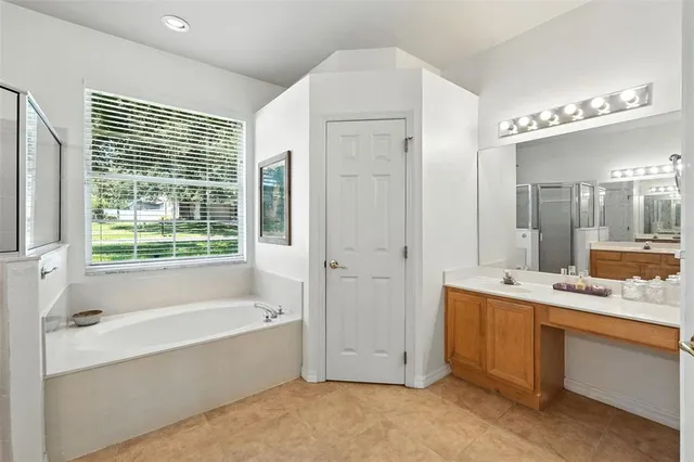a spacious bathroom with a tub sink and mirror