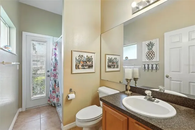 a bathroom with a granite countertop toilet a sink and a mirror