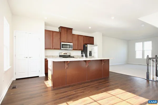 a large kitchen with granite countertop a stove a sink dishwasher and a refrigerator with wooden floor