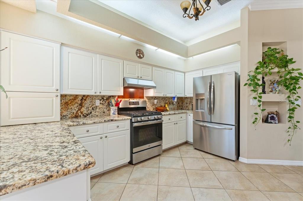 13624 Cooper Road Spring Hill, FL 34609 - Photo 27 of 75 a kitchen with granite countertop a refrigerator and a stove top oven