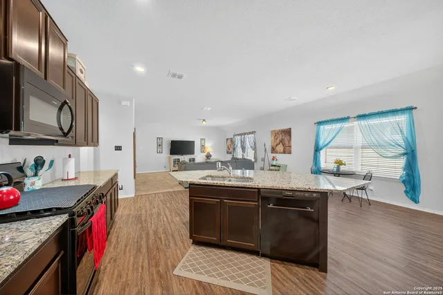 a kitchen with stainless steel appliances granite countertop a sink refrigerator and cabinets
