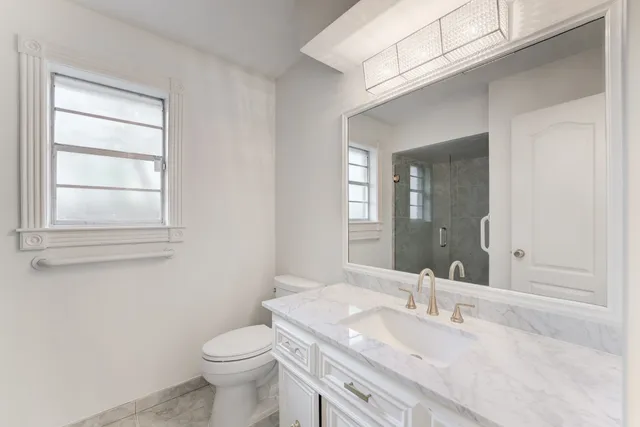 a bathroom with a granite countertop toilet a sink and mirror