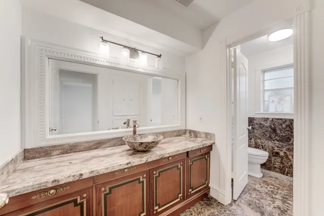 a bathroom with a granite countertop sink a toilet and a mirror