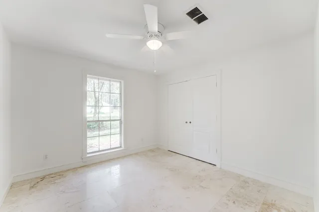 an empty room with windows and ceiling fan view