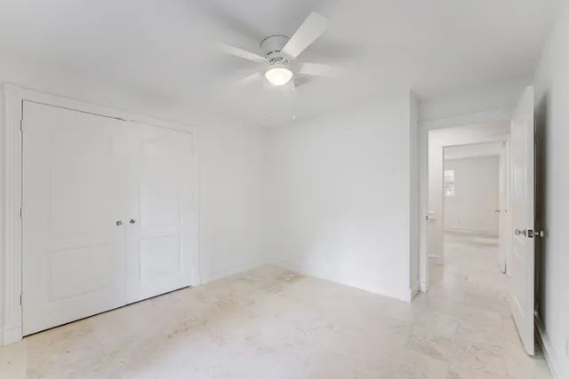 an empty room with a ceiling fan and a window