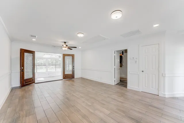 an empty room with wooden floor fan and windows
