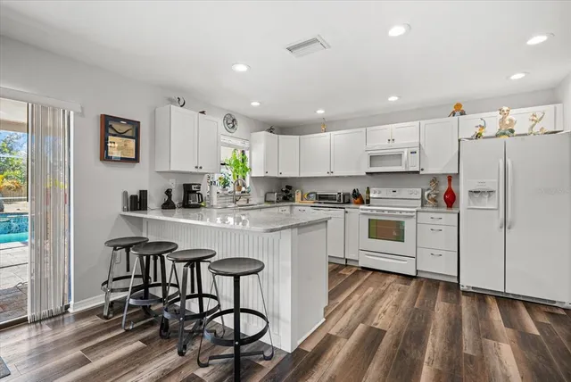 a kitchen with granite countertop white cabinets and stainless steel appliances
