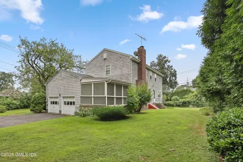 a view of a house with a big yard potted plants and large tree