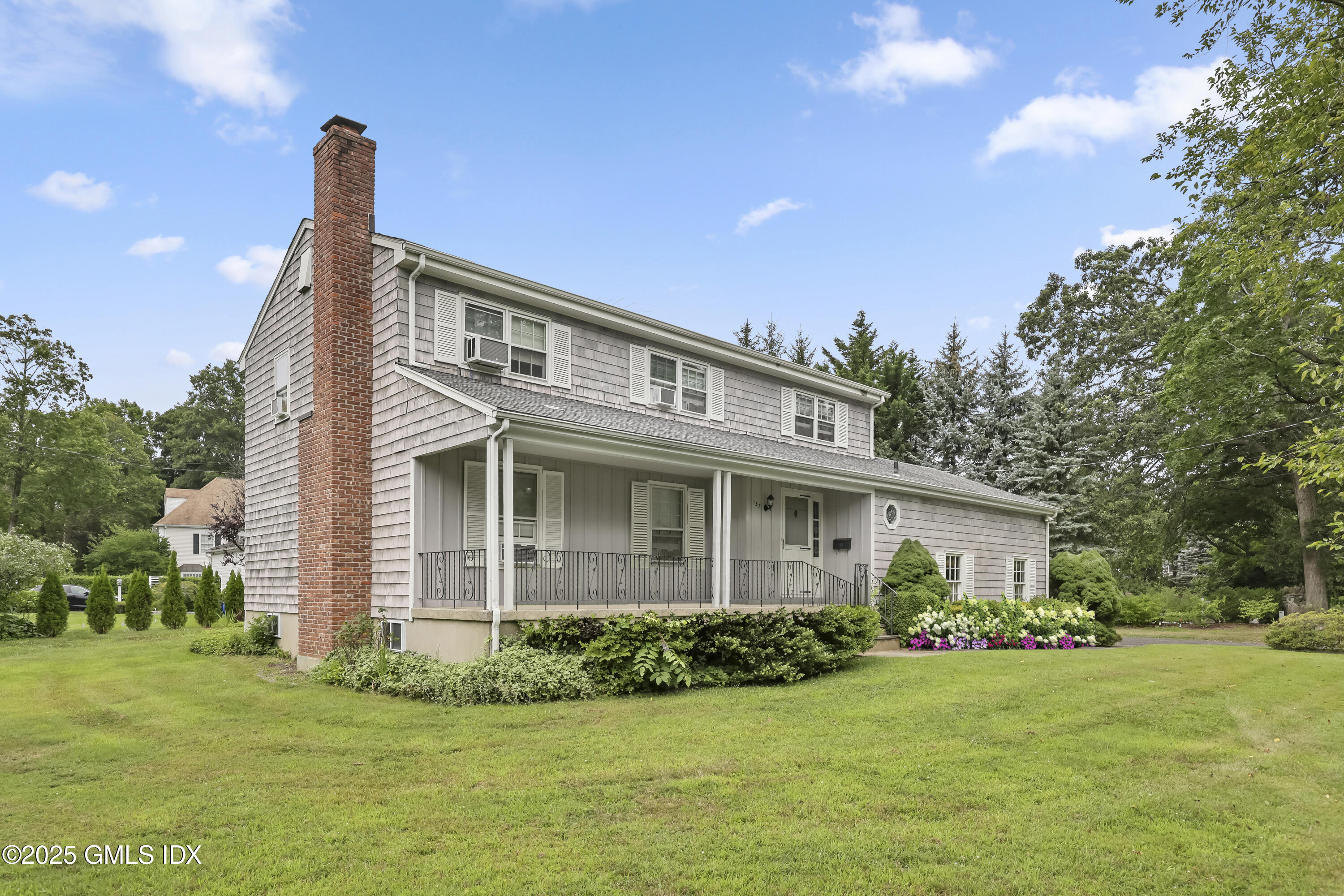 137 Shore Road Old Greenwich, CT 06870 - Photo 2 of 15 a front view of a house with a garden and plants