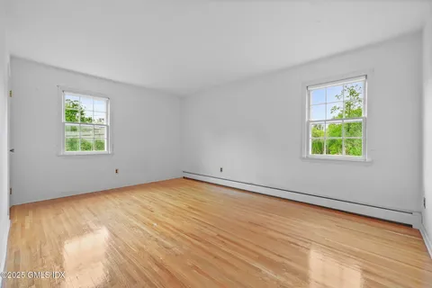 a view of an empty room with a window and wooden floor