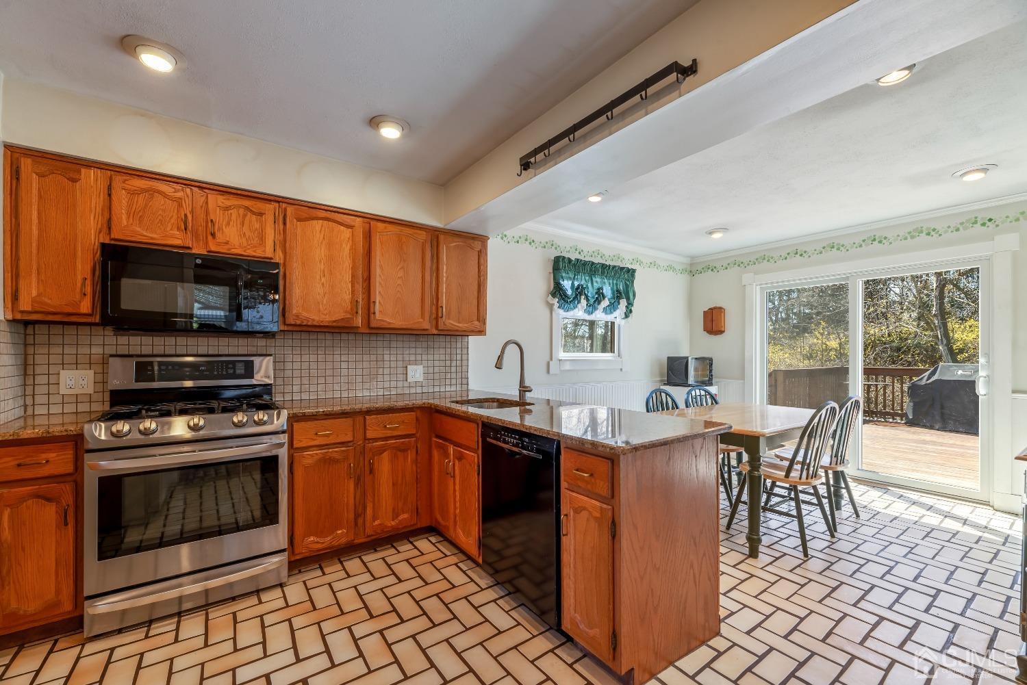 2 Perry Road East Brunswick, NJ 08816 - Photo 10 of 32 a kitchen with stainless steel appliances granite countertop a stove top oven a sink dishwasher a dining table and chairs with wooden floor