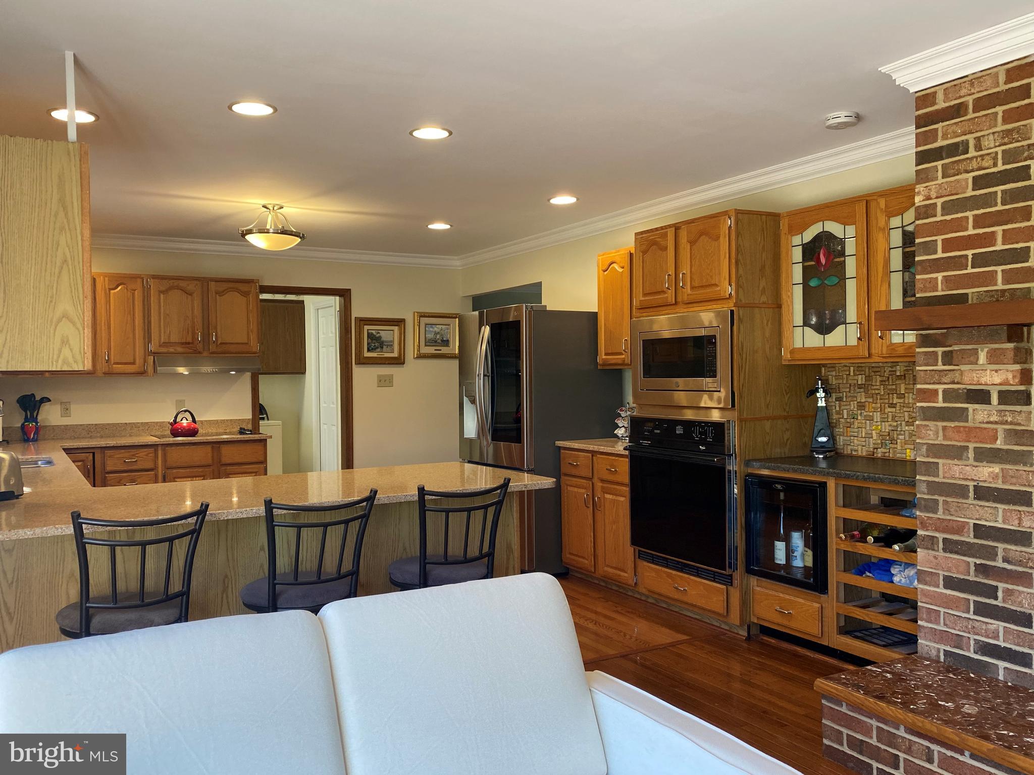 970 St George Barber Road Davidsonville, MD 21035 - Photo 32 of 69 a kitchen with stainless steel appliances kitchen island granite countertop a refrigerator a stove a sink a dining table and chairs with wooden floor