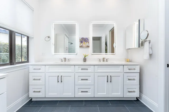 a bathroom with double vanity white cabinets and a mirror