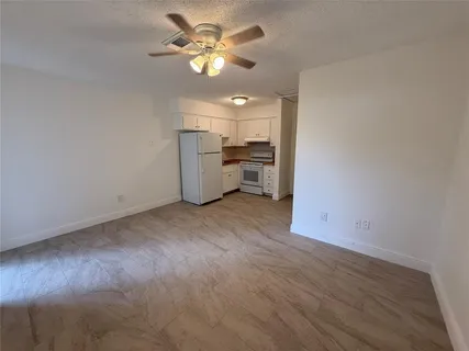a view of a kitchen with a sink a ceiling fan and stainless steel appliances