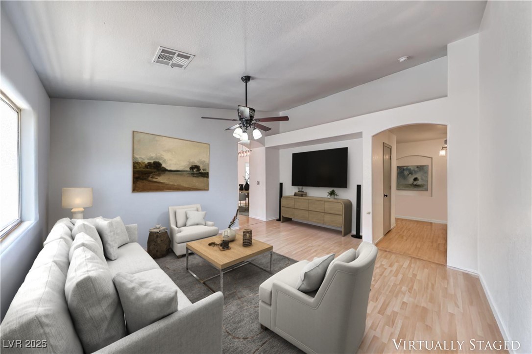 990 Ridge Path Avenue Henderson, NV 89015 - Photo 2 of 41 Living area featuring arched walkways, light wood finished floors, ceiling fan, and plenty of natural light