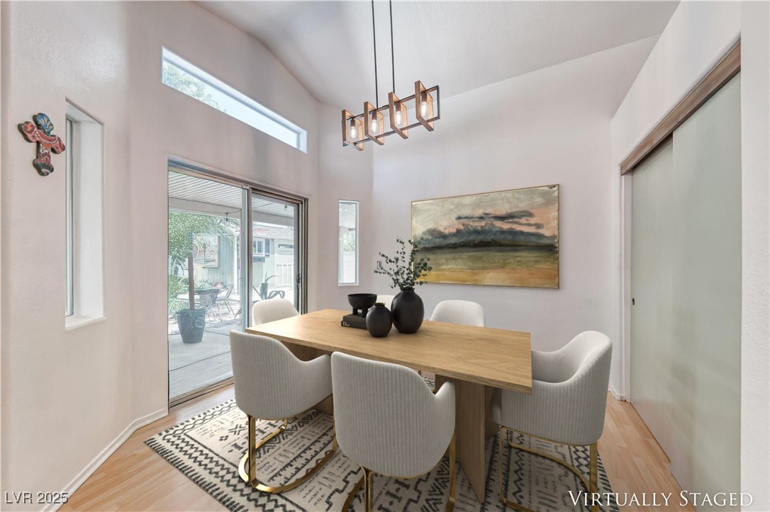 990 Ridge Path Avenue Henderson, NV 89015 - Photo 6 of 41 Dining area with light wood-style floors, a chandelier, and a towering ceiling