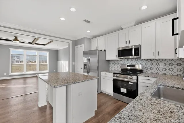 a kitchen with granite countertop a sink and a white wooden cabinets