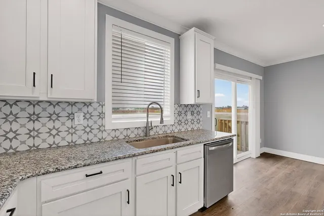 a kitchen with granite countertop cabinets stainless steel appliances a sink and a wooden floor