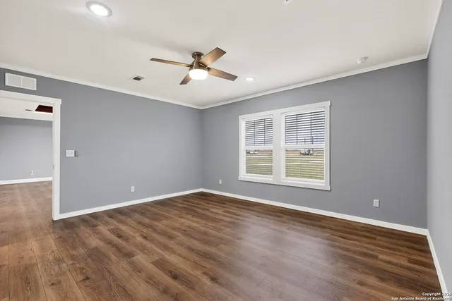 a view of an empty room with window and wooden floor