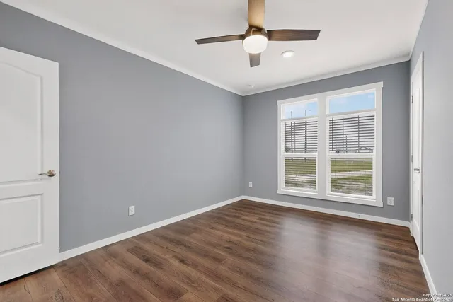 an empty room with wooden floor and a ceiling fan