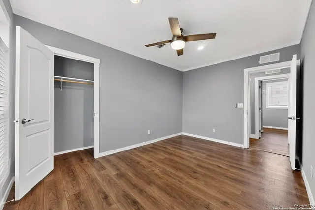an empty room with wooden floor closet and windows