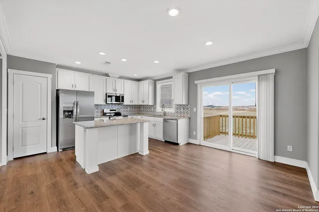 a kitchen with granite countertop stainless steel appliances a refrigerator and a stove top oven