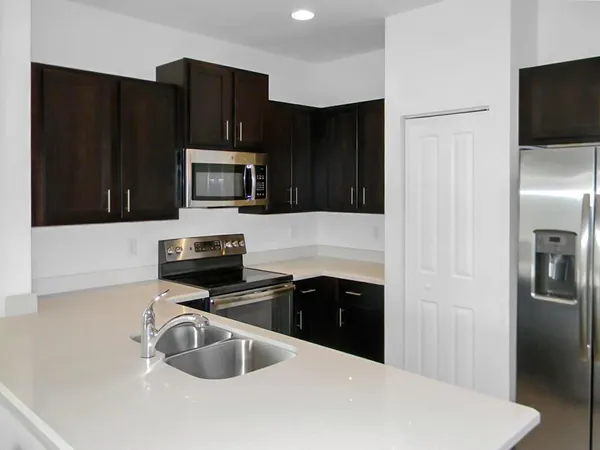a kitchen with granite countertop a refrigerator and a stove top oven