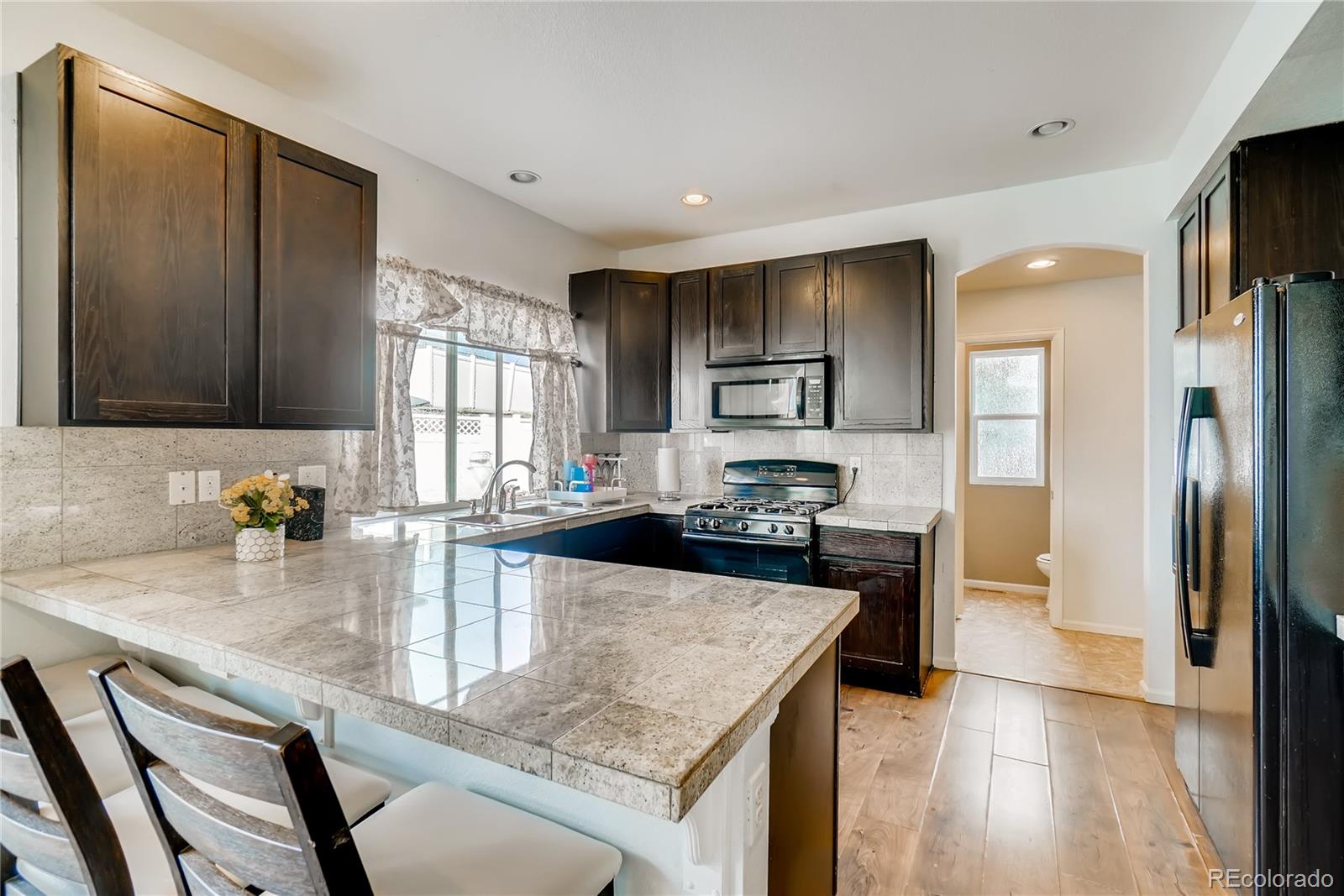 20761 Randolph Place Denver, CO 80249 - Photo 5 of 25 a kitchen with a refrigerator a sink a stove cabinets and living room view