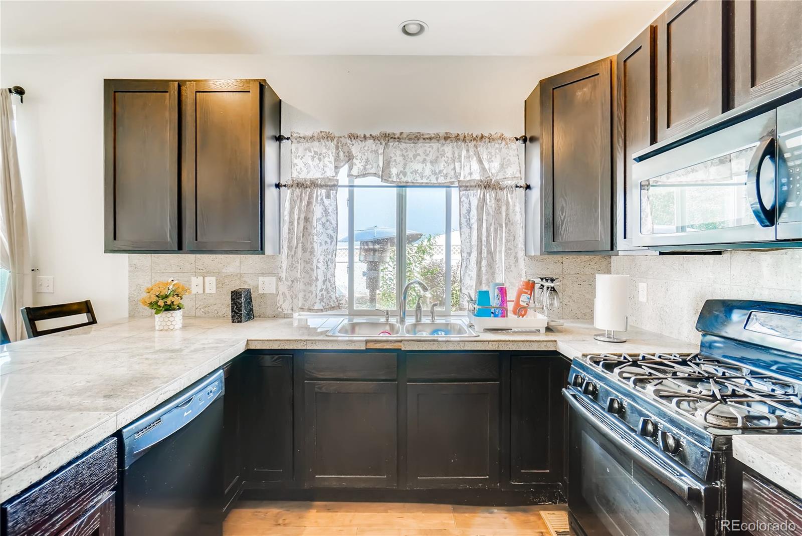 20761 Randolph Place Denver, CO 80249 - Photo 6 of 25 a kitchen with kitchen island granite countertop a sink stove and cabinets