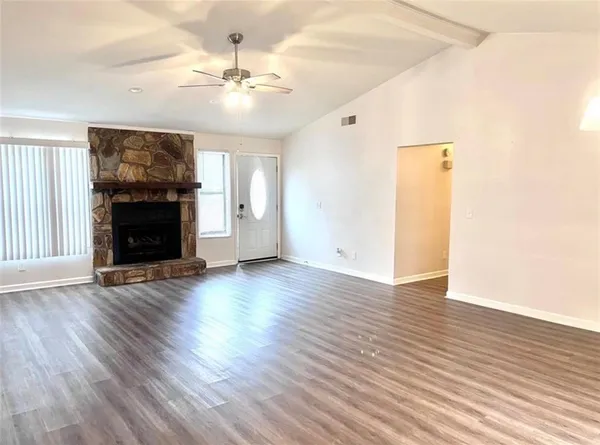 an empty room with wooden floor fireplace and window