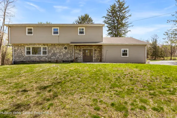 a front view of house with yard and trees in the background