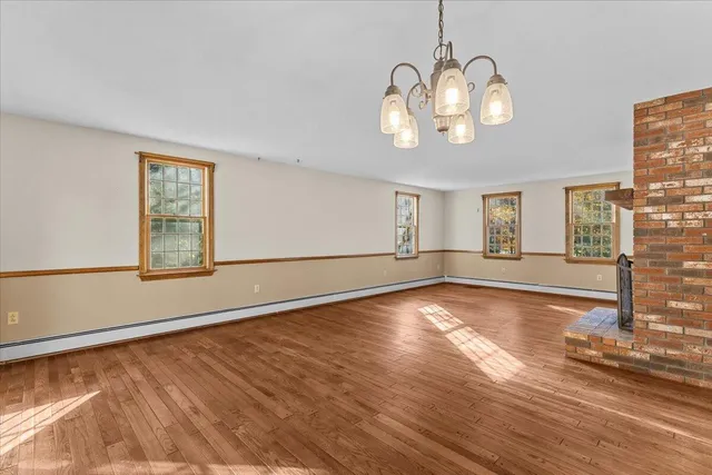 a view of an empty room with window and wooden floor