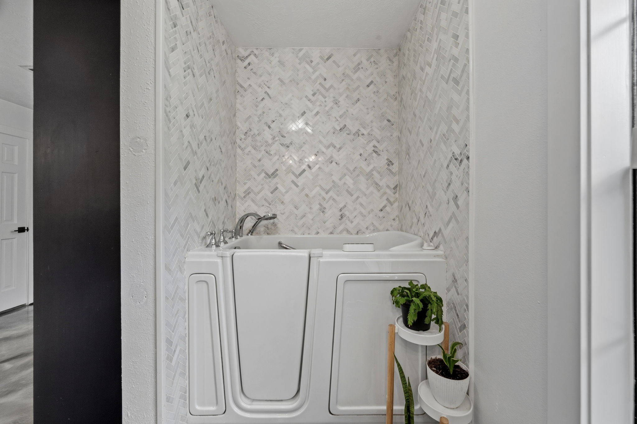 18 East Old Field Road Huffman, TX 77336 - Photo 20 of 35 Beautifully updated walk-in soaking tub surrounded by elegant marble-inspired tilework, offering both comfort and accessibility within this thoughtfully designed spa-like bath.