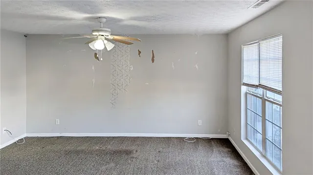 an empty room with windows and fan