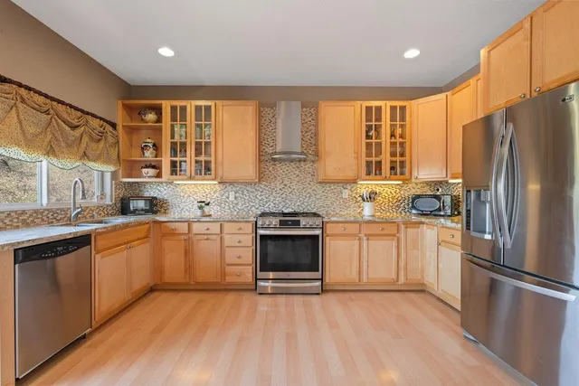 a kitchen with granite countertop wooden floors stainless steel appliances and window