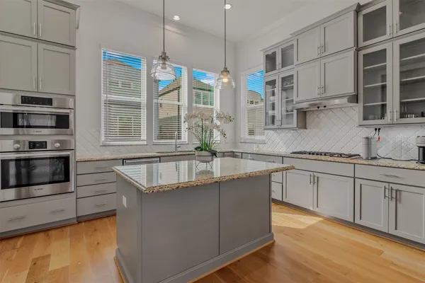 a kitchen with stainless steel appliances granite countertop a sink a stove and a wooden floors
