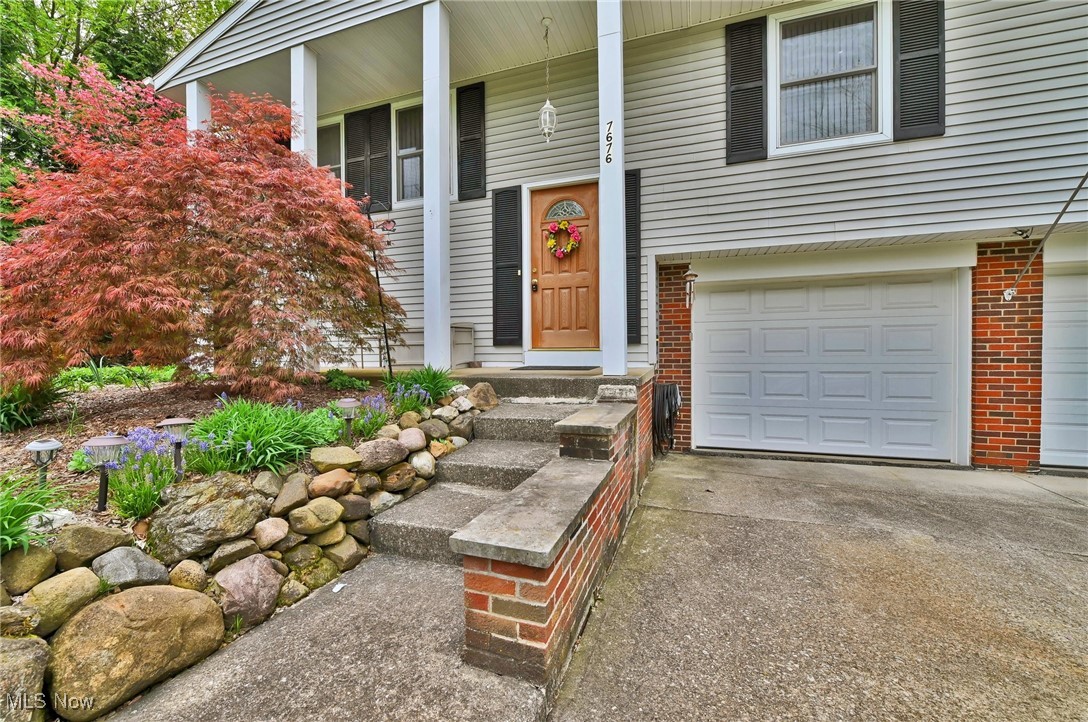 View of exterior entry with brick siding, an attached garage, and concrete driveway