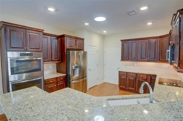 a kitchen with stainless steel appliances granite countertop a refrigerator a stove and a sink