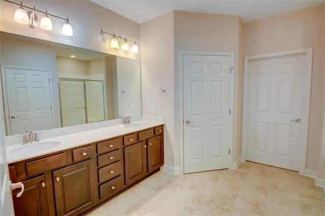 a spacious bathroom with a double vanity sink a large mirror and a