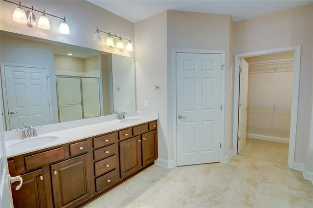 a spacious bathroom with a double vanity sink a large mirror and a shower
