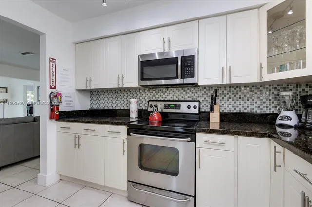 a kitchen with granite countertop white cabinets and stainless steel appliances