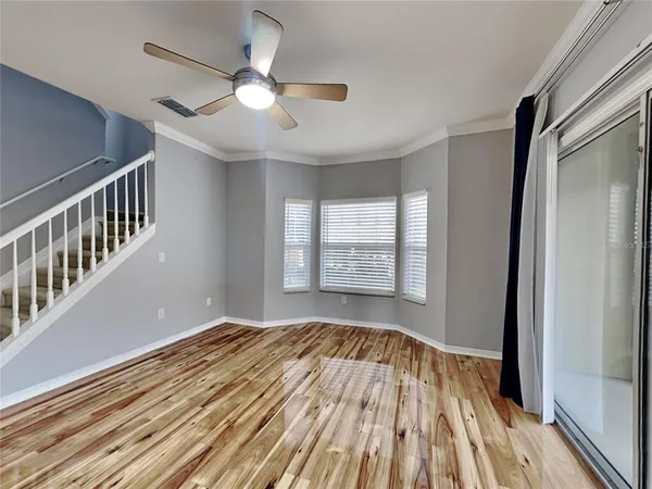an empty room with wooden floor fan and windows