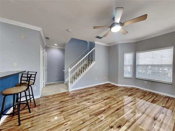 a view of a livingroom with wooden floor and a ceiling fan