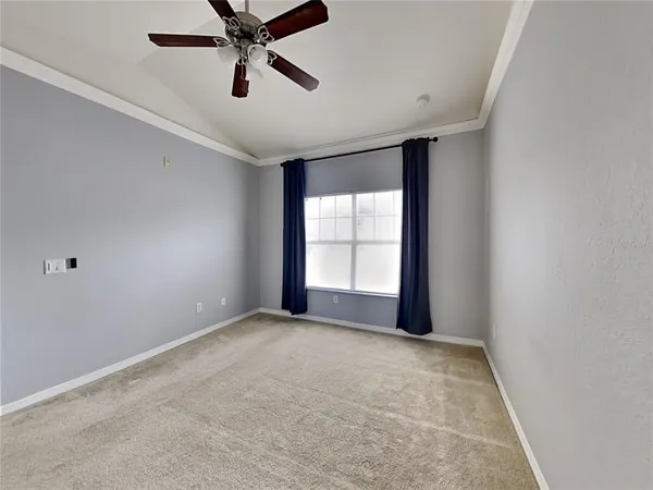 an empty room with windows and ceiling fan