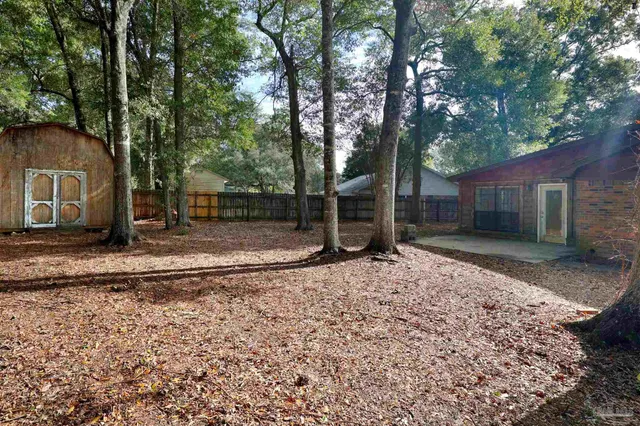 a backyard of a house with barbeque oven and large trees