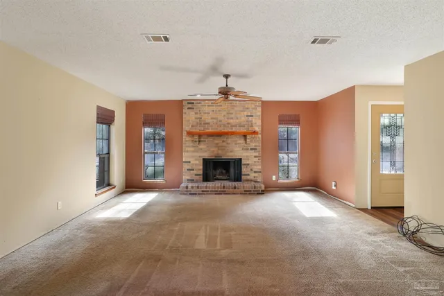 a view of an empty room with a fireplace and a window
